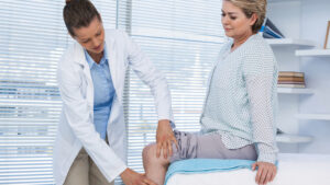 a doctor examines a woman's knee in a doctor's office for Denver stem cell therapy for knees
