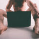Young naked man watching pornography and masturbating.