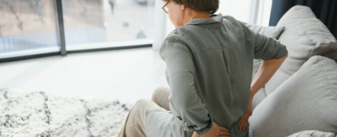 Denver Stem Cell therapy: A female seated on a sofa, experiencing discomfort in her back