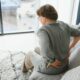 Denver Stem Cell therapy: A female seated on a sofa, experiencing discomfort in her back